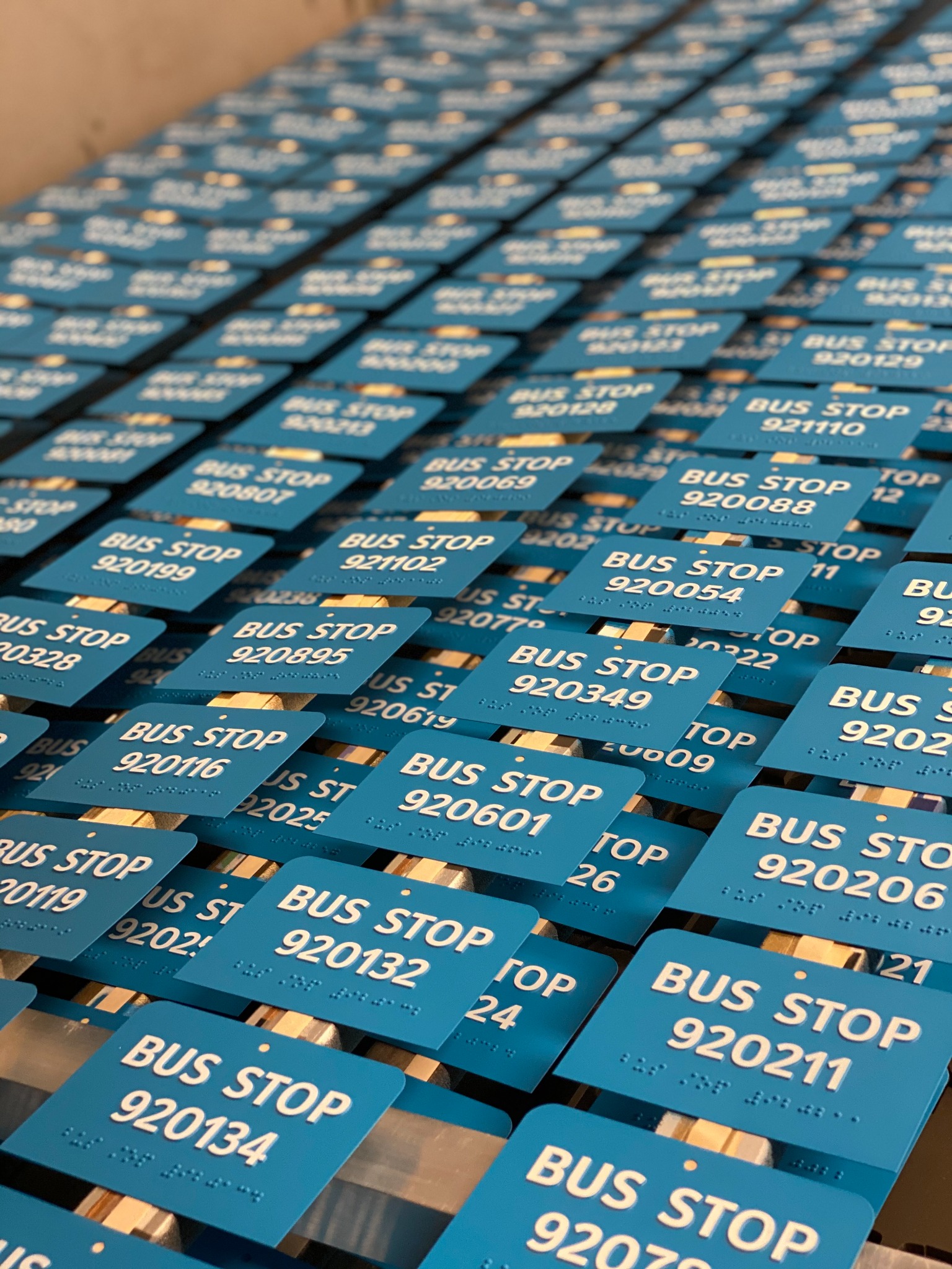 Rows of blue bus stop signs with tactile lettering and Braille